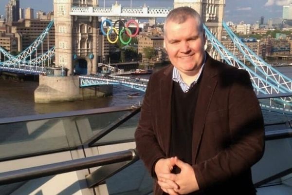 Ken Hayes standing in front of Tower Bridge with Olympic Rings