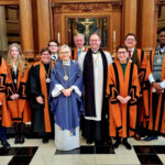 Newly installed Guild of St Bride members standing in front of the altar at St Bride's CHurch, Fleet St