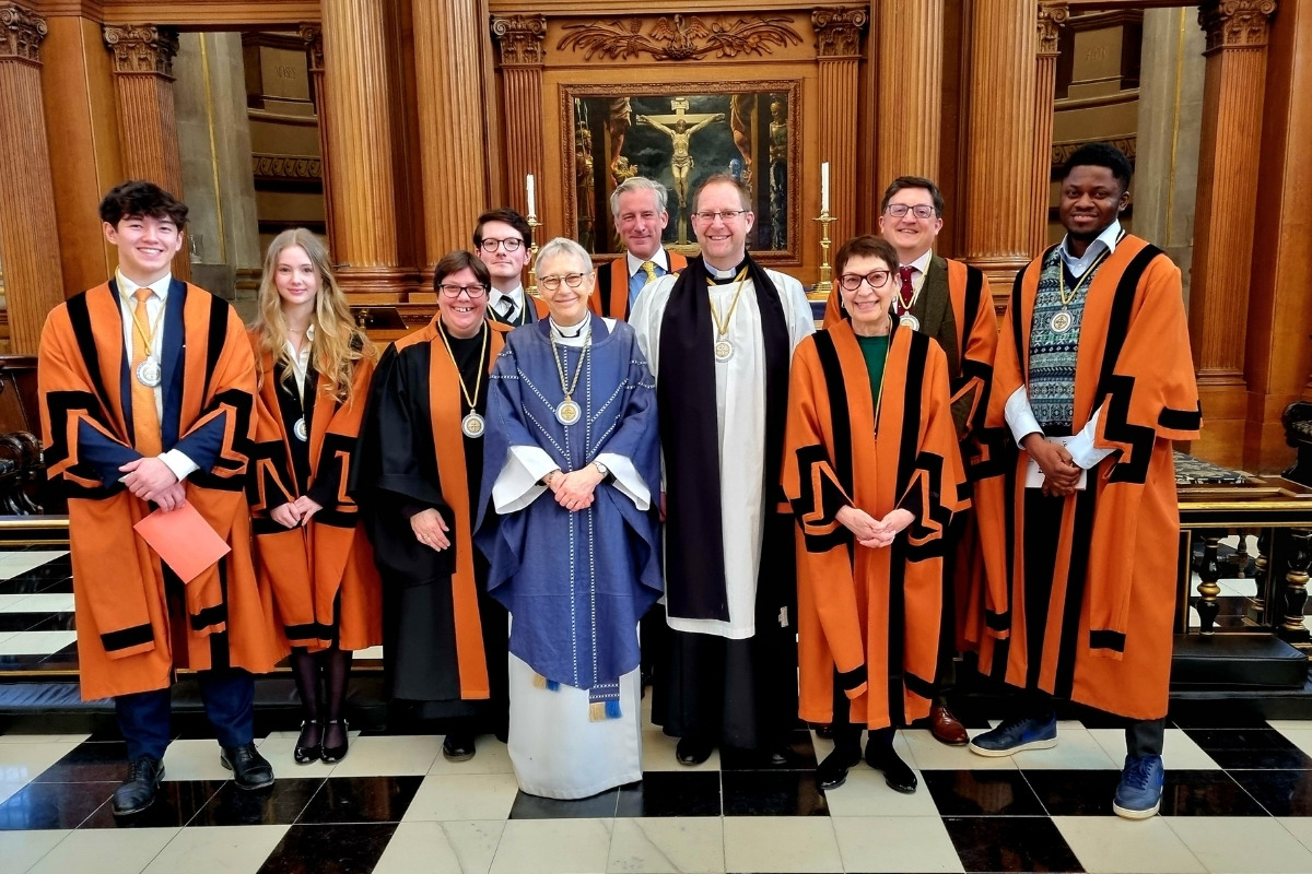 Newly installed Guild of St Bride members standing in front of the altar at St Bride's CHurch, Fleet St
